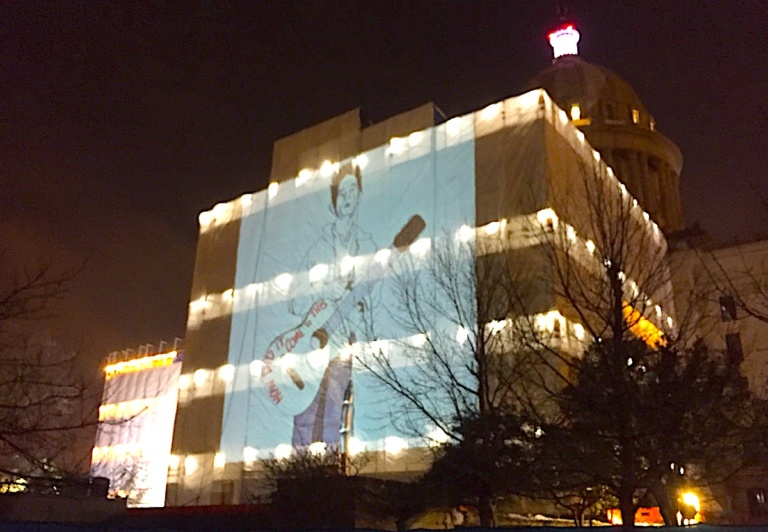 Giant Woody Guthrie projected onto Oklahoma Capitol