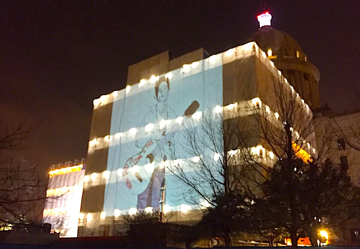 Giant Woody Guthrie projected onto Oklahoma Capitol